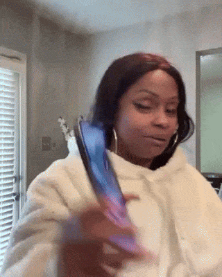 a woman in a white hoodie is holding a cell phone .