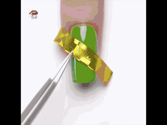 a pair of tweezers is holding a piece of gold foil on a green nail