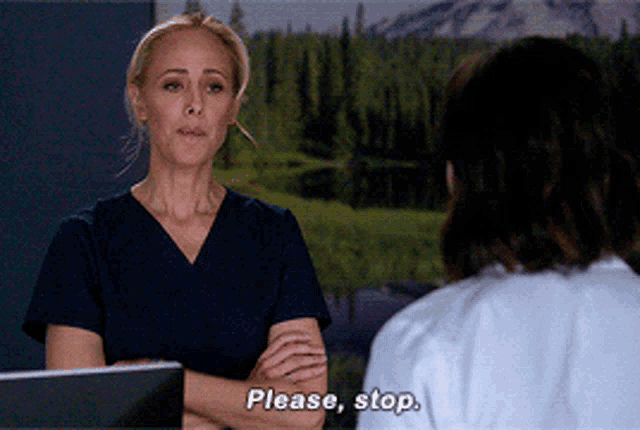 a woman in scrubs is talking to another woman who says please stop