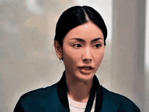 a close up of a woman wearing a blue jacket and earrings .