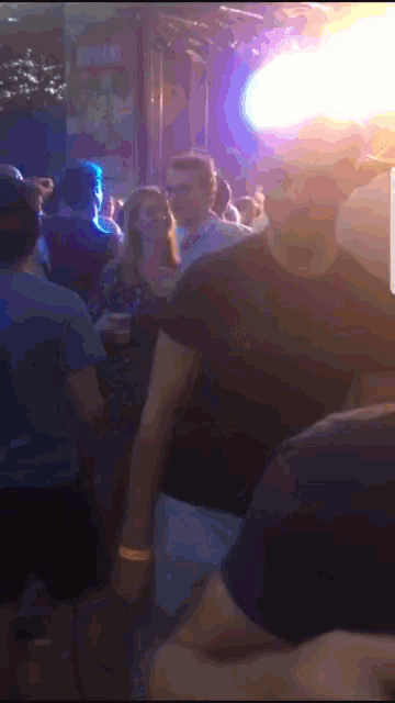 a crowd of people are gathered in a dark room with purple lights behind them