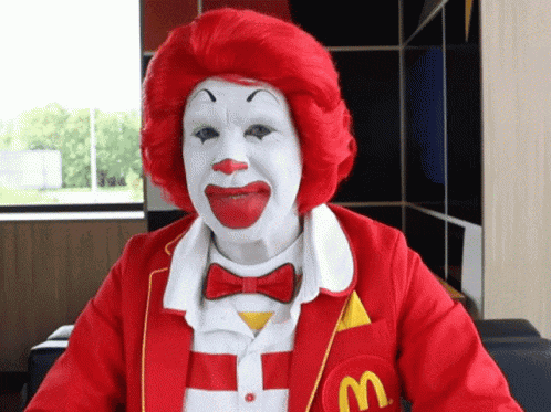 a mcdonald 's clown is wearing a red jacket with a m on it