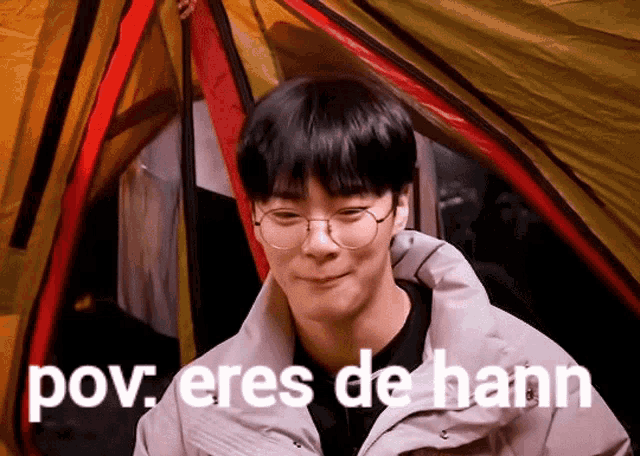 a man wearing glasses is standing in front of a tent with the words pov eres de hann written below him