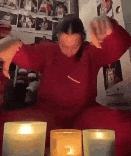 a person in a red sweater is sitting in front of candles .