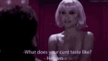 a woman in a pink wig is talking to a man in a room .