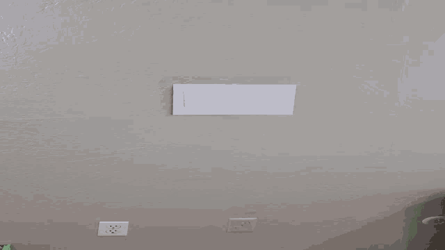 a dirty wall with a white electrical outlet and a piece of paper on it