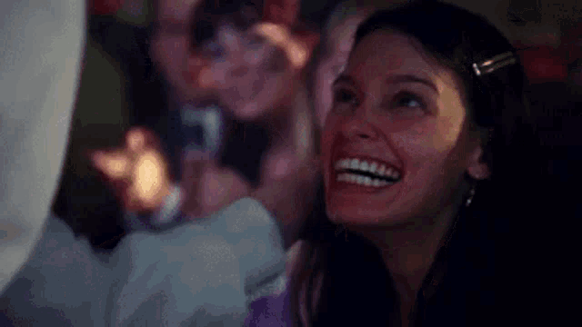 a woman is laughing while sitting in front of a crowd of people .