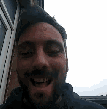a man with a beard is smiling with his eyes closed