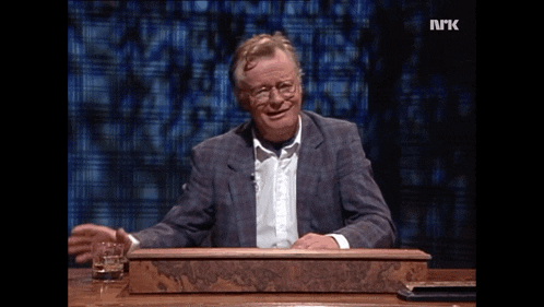 a man sitting at a desk with the letters nrk on the bottom of his screen