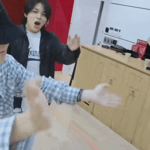 a man in a plaid shirt is standing in a kitchen with his hands outstretched