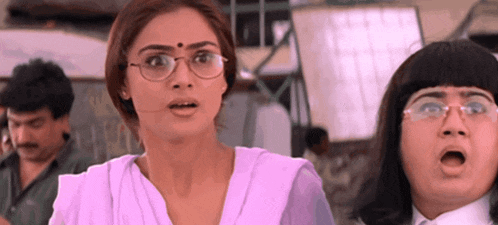 a woman wearing glasses looks surprised while standing next to a boy