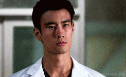 a close up of a man wearing a white lab coat and a black shirt