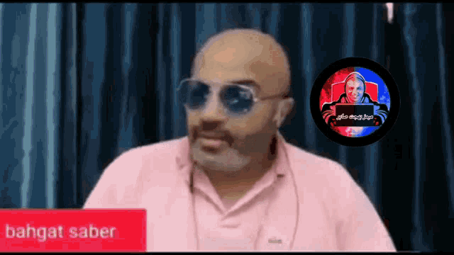 a bald man wearing sunglasses and a pink shirt with the word bahgat saber on the bottom right