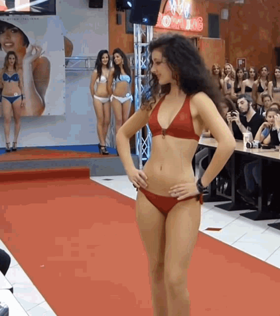 a woman in a bikini walks down a red carpet