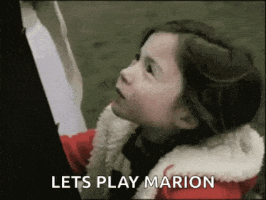 a little girl in a red jacket is standing next to a man in a suit and says `` lets play marion '' .