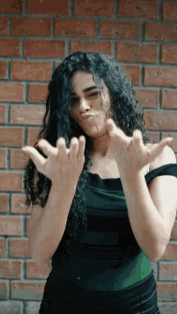 a woman with curly hair is making a funny face with her hands