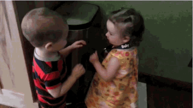 a boy and a girl are standing next to each other and the girl is wearing a baby bib .