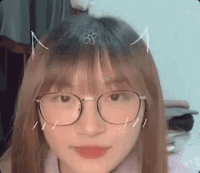 a close up of a girl wearing glasses and a flower in her hair .