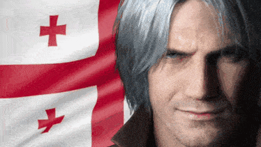 a man with gray hair stands in front of a flag with a red cross on it