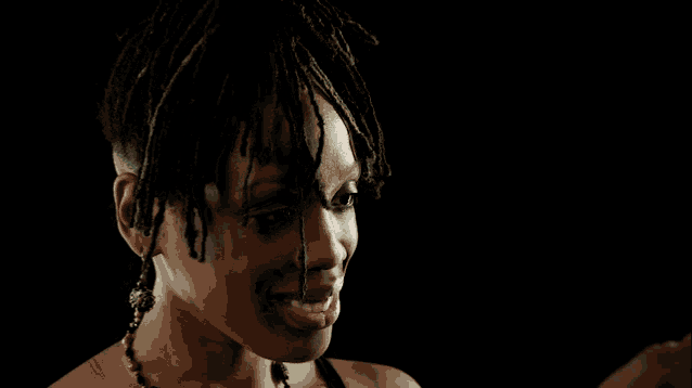 a woman with green dreadlocks looks at herself in the mirror