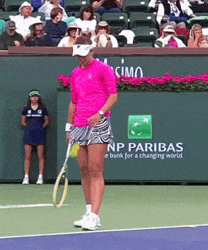 a woman holding a tennis racquet on a tennis court with a np paribas sign in the background