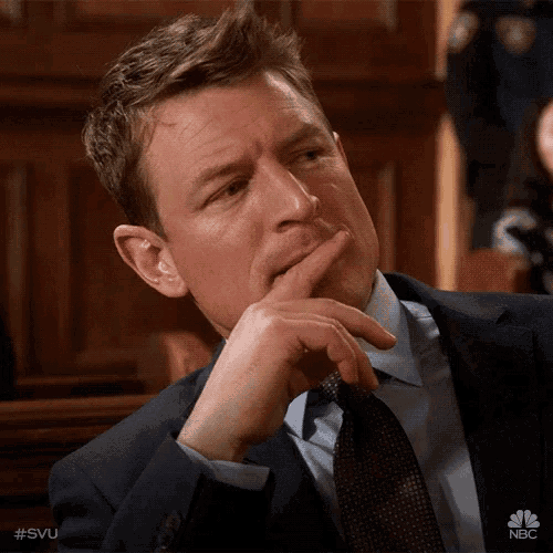 a man in a suit and tie is sitting in a courtroom with his hand on his chin ..