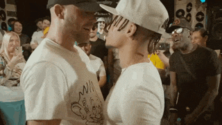 two men standing next to each other with one wearing a white shirt that says win