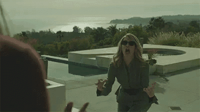 a woman in a suit and sunglasses is screaming at a man in front of a pool .