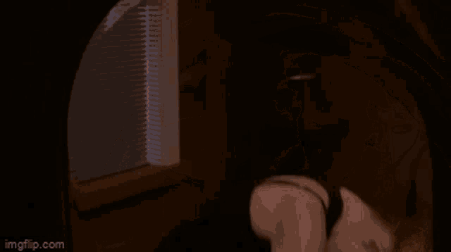 a woman in a black tank top is looking at herself in the mirror .