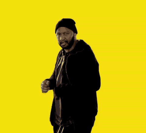 a man with a beard is wearing a black jacket and a black beanie .