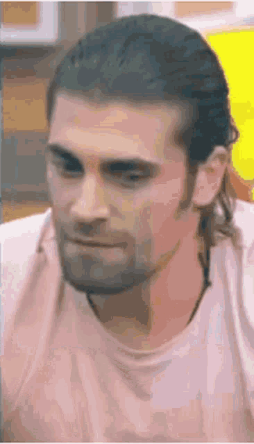 a man with long hair and a beard is wearing a white shirt and looking at the camera .