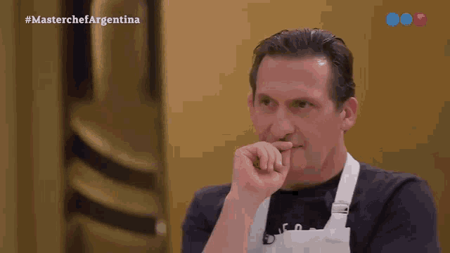 a man wearing an apron and a black shirt is on a television show called master chef argentina