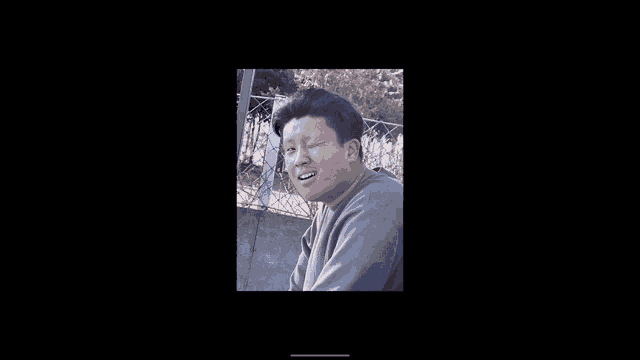 a man in a grey sweater is making a funny face
