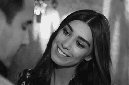a black and white photo of a woman smiling while looking at a man .