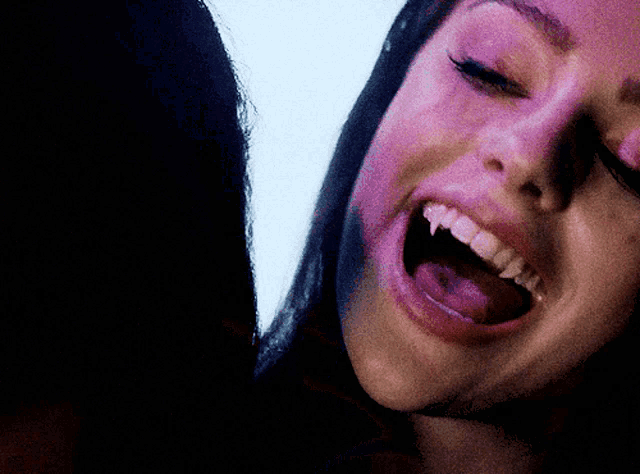 a close up of a woman 's face with her mouth wide open