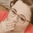 a close up of a woman wearing glasses covering her mouth .