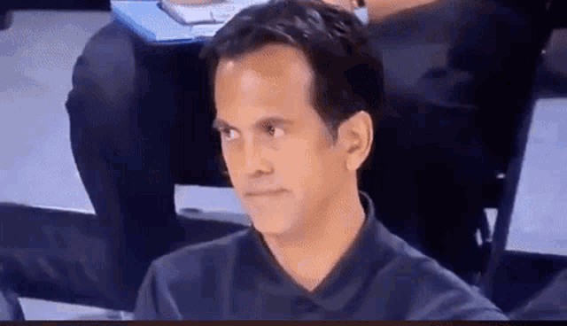 a man in a black shirt is sitting in a chair looking at something .