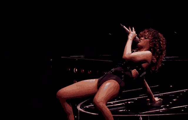 a woman singing into a microphone while kneeling down