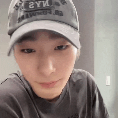a close up of a person wearing a baseball cap and a gray shirt .