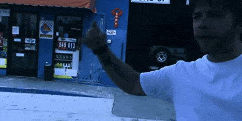 a man giving the middle finger in front of a store that has the number 049 on it