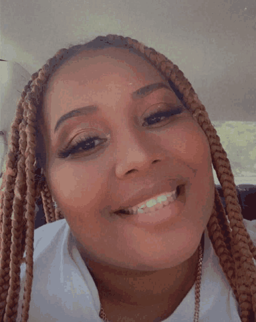 a woman with braids is smiling for the camera and wearing a white shirt