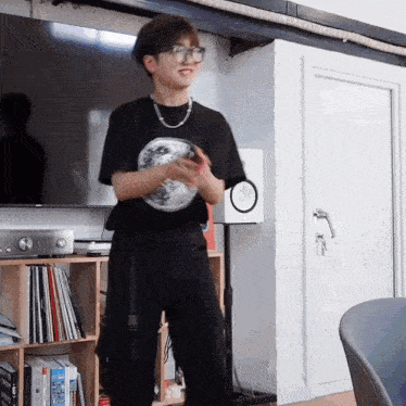 a man wearing glasses and a black shirt stands in front of a white speaker