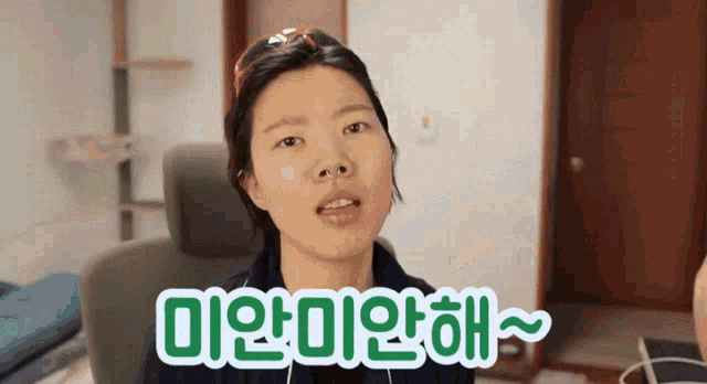 a woman is sitting in a chair with a green sign that says " 미안 미안해 "