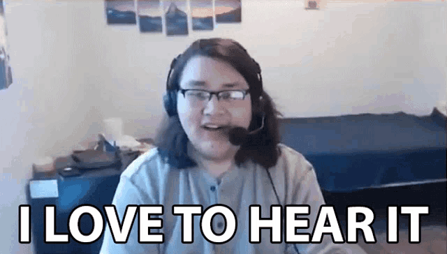 a man wearing headphones and glasses is sitting in front of a computer screen and says `` i love to hear it '' .