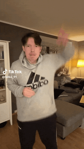 a man wearing a grey adidas hoodie is dancing