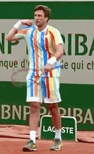 a man in a colorful shirt is holding a tennis racket in front of a bnp paribas sign