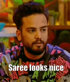 a man with a beard is wearing a colorful sweater and says saree looks nice .