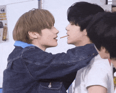 two boys are kissing each other with a stick in their mouths