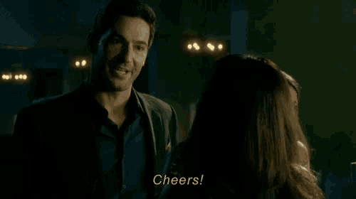 a man in a suit holds a glass of whiskey in front of a woman who says cheers
