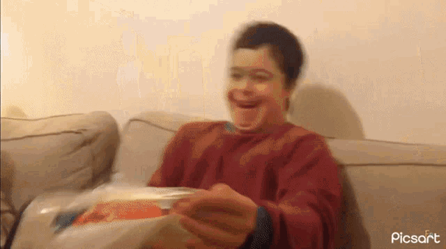 a boy is sitting on a couch with a blurred image of him and the words picsart on the bottom right